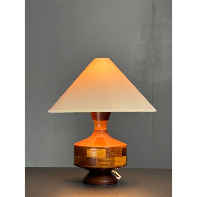 English table lamp from the 1950s–60s with a hand-turned wooden base featuring geometric inlay work. The design centers on...