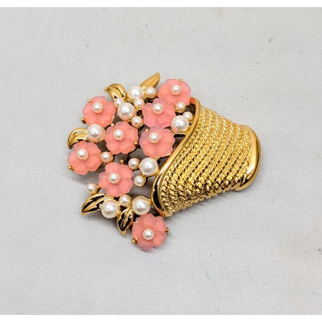 1980s goldtone molded pink resin flowers with faux-pearl centers and accents in a basket brooch with a security clasp....