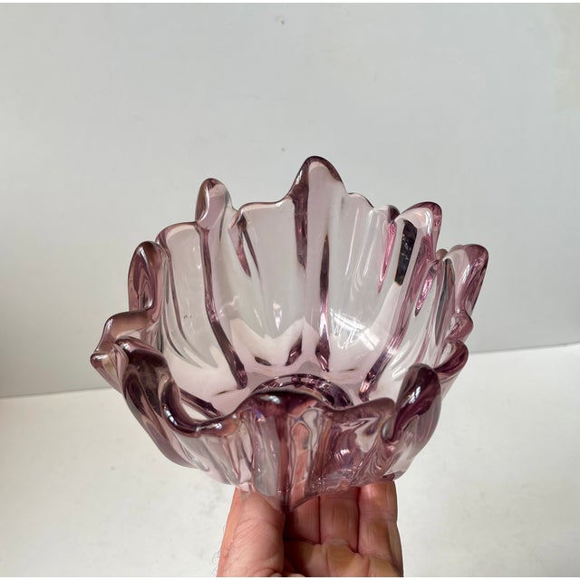 A sculptural freeform art glass dish/bowl executed in purple tinted pink crystal glass. Designed by Bosse Rubin and made...