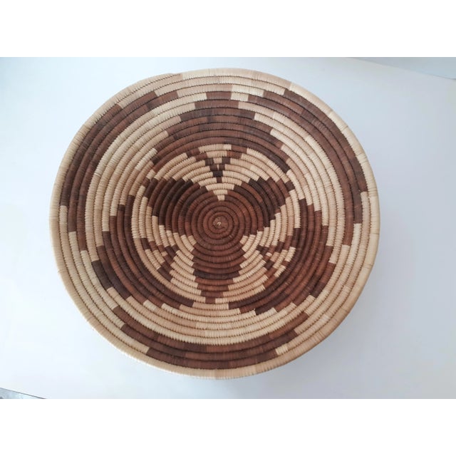 Two vintage African Tribal style hand woven coil baskets. The two basket set consists of one olla basket with a geometric...