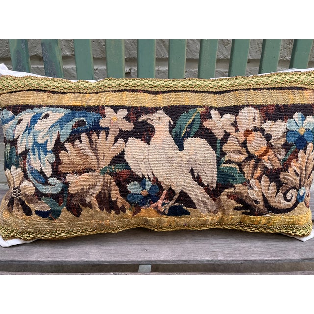 This decorative pillow is upholstered with an authentic 18th-century tapestry, showcasing a beautifully detailed bird...