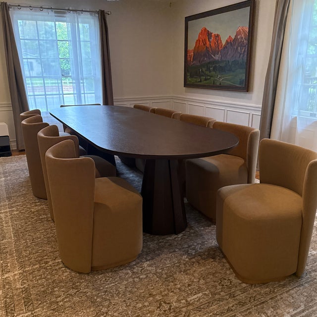 Elegant contemporary dining set featuring a large oval table in a rich chocolate oak finish with a sculptural double...