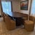 Elegant contemporary dining set featuring a large oval table in a rich chocolate oak finish with a sculptural double...