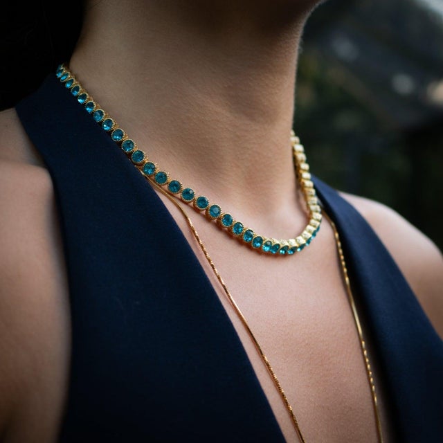 The Aquamarine Tennis Mystic Necklace is a breathtaking choker-style piece crafted on a bronze base with luxurious gold...