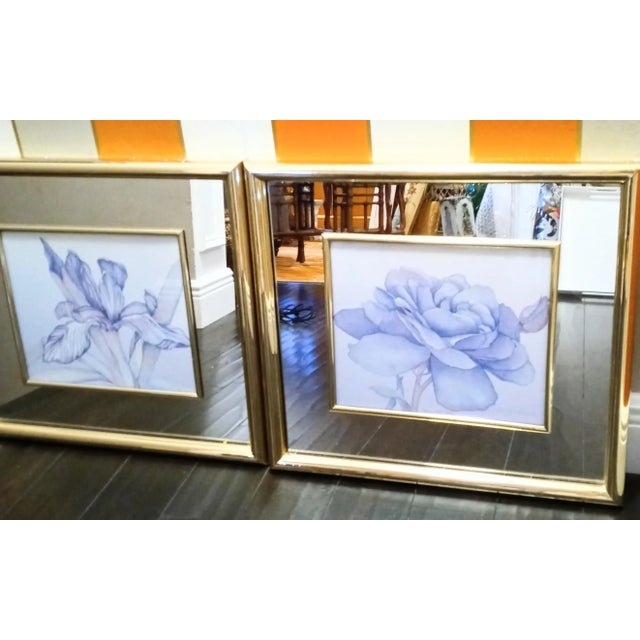 A stunning pair of mirrored framed watercolor floral prints. The prints are signed but I can't make out the signature....