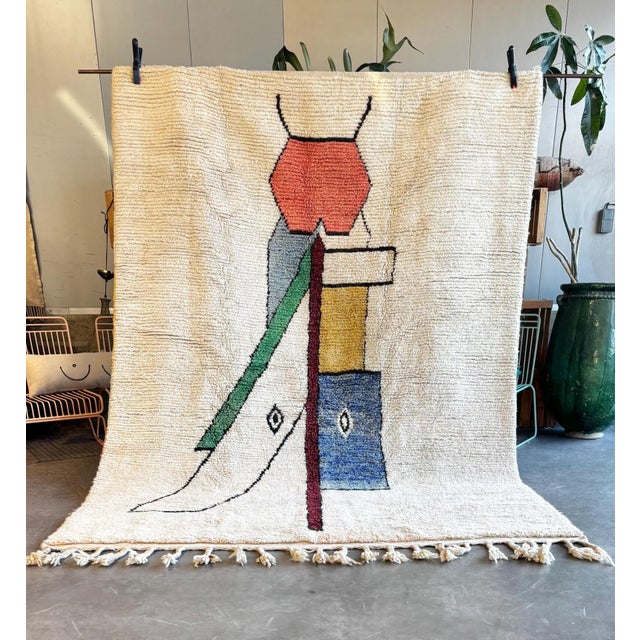 This Moroccan rug is showcasing a unique and intricate geometric pattern. The design consists of an array of...