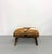 A striking vintage ottoman upholstered in genuine brown and white cowhide, featuring a clean square cushion atop an...