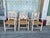 Hand-carved wooden armchairs with a distressed white and pastel iridescent finish. Each chair has a woven rush seat and...