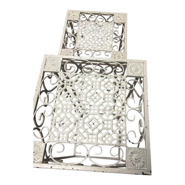 A striking pair of vintage graduated metal plant stands or display pedestals featuring elaborate openwork construction and...