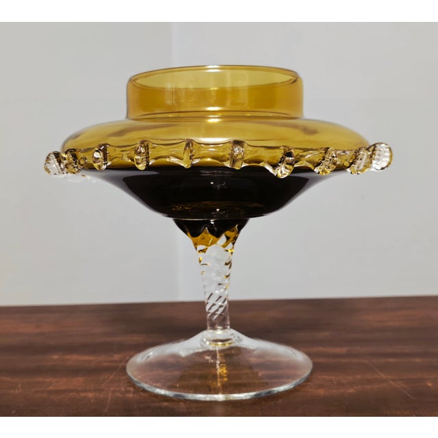 A striking mid‑century hand‑blown art glass compote featuring a rich amber bowl with applied clear‑glass prunts and a...