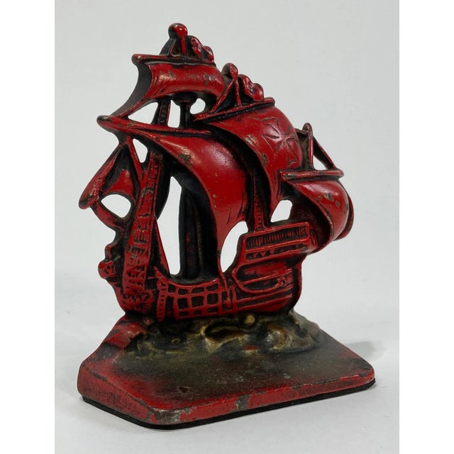 Vintage heavy cast iron pirate ship doorstop. Ship and sails are a rich red with a bronzed base. Cross to one of the...