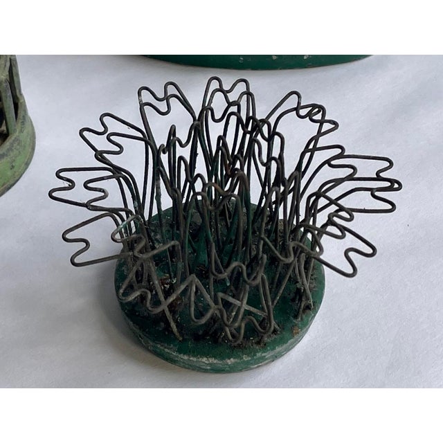 This is a mismatched set of three flower holders or “Frogs.” Two are Blue Ribbon brand, and one is a cage without brand...