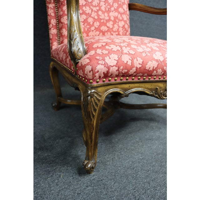 French Louis XV-style open armchair featuring a carved wood frame with graceful cabriole legs and decorative apron...