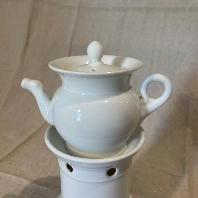 An elegant antique French Old Paris porcelain teapot and tea warmer stand from the late 19th Century. The set is...