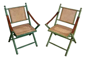 Pair of 1970s folding safari chairs in weathered faux bamboo with caned backs and seats