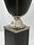 A striking neoclassical-style decorative urn featuring a leather-wrapped body with contrast stitching, topped by a...