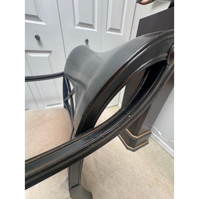 A striking pair of Regency-style armchairs featuring ebonized frames with gilt accents and beautifully hand-decorated...