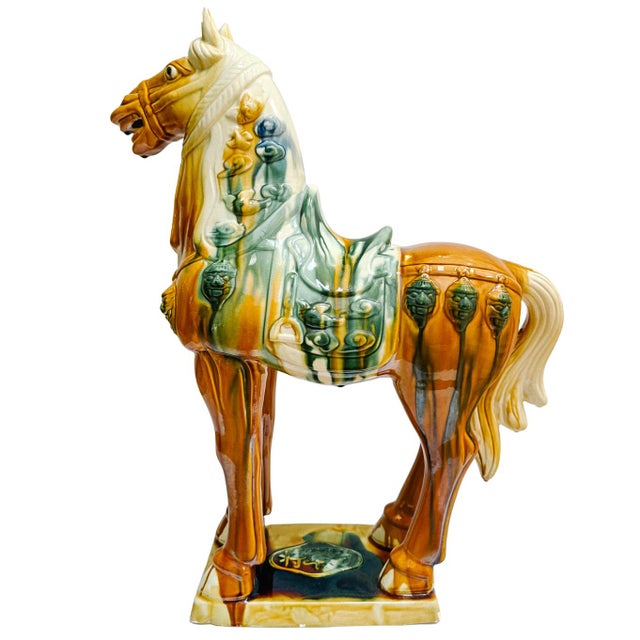 A grand, sculptural Tang Dynasty-style ceramic horse standing an impressive 23 inches tall. This large-scale piece is a...