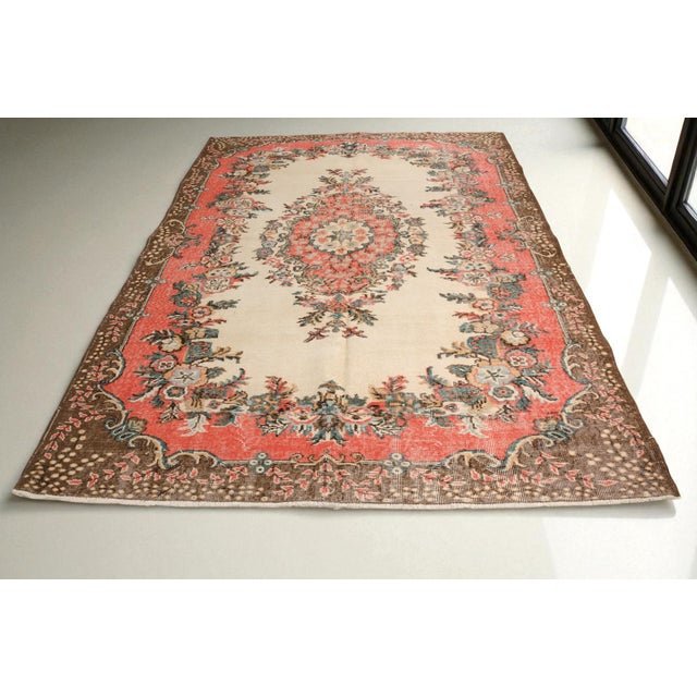 This is a vintage Turkish Oushak rug from the Mid 20th Century. The piece was hand-knotted.