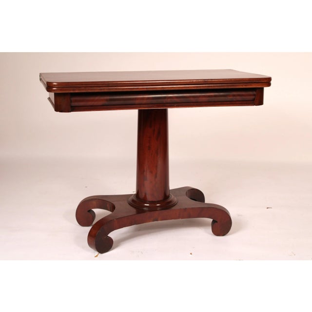 Neo classical style mahogany games table, circa 1840. With a rectangular flame mahogany top with rounded front corners, a...