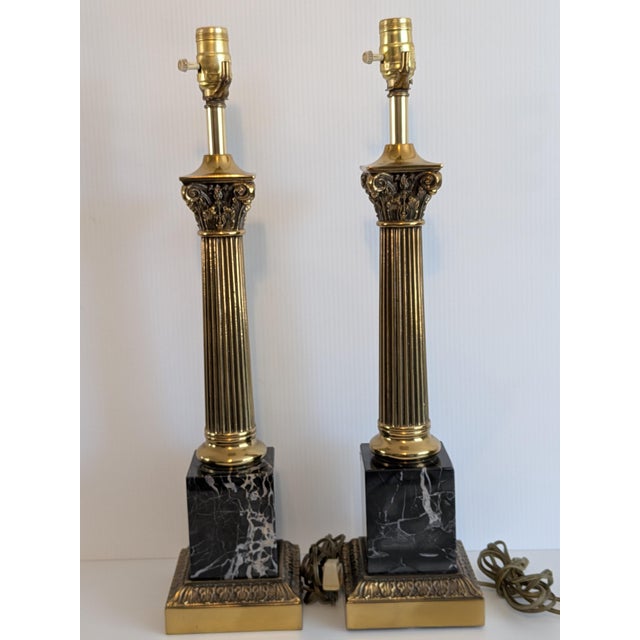 A pair of brass & marble French Empire style table lamps. Fluted brass corinthian columns topped with cast scrolled...