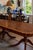 An impressive Regency-style dining table featuring a richly figured burl wood top accented with an elegant brass Greek key...