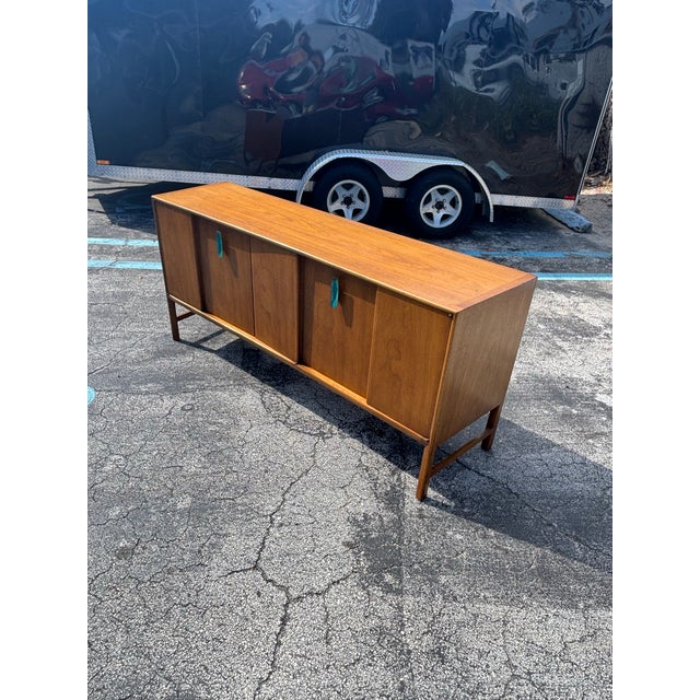 Refined and architectural, this vintage mid-century walnut credenza was designed by Raymond Sobota for Mount Airy...