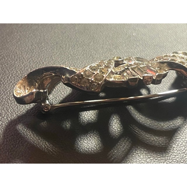 Early Crown Trifari Art Deco style brooch featuring a mix of pavé-set round rhinestones along flowing interlocking curves...
