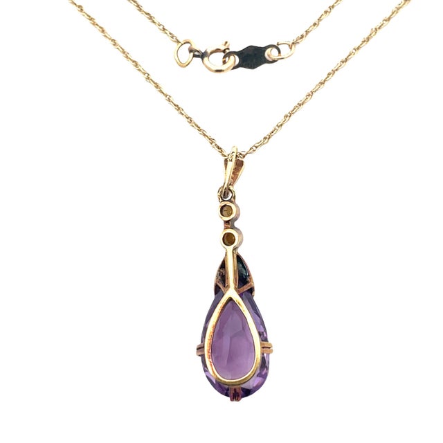 Elegant vintage pendant necklace crafted in 14K yellow gold, featuring a faceted pear-shaped amethyst accented by delicate...