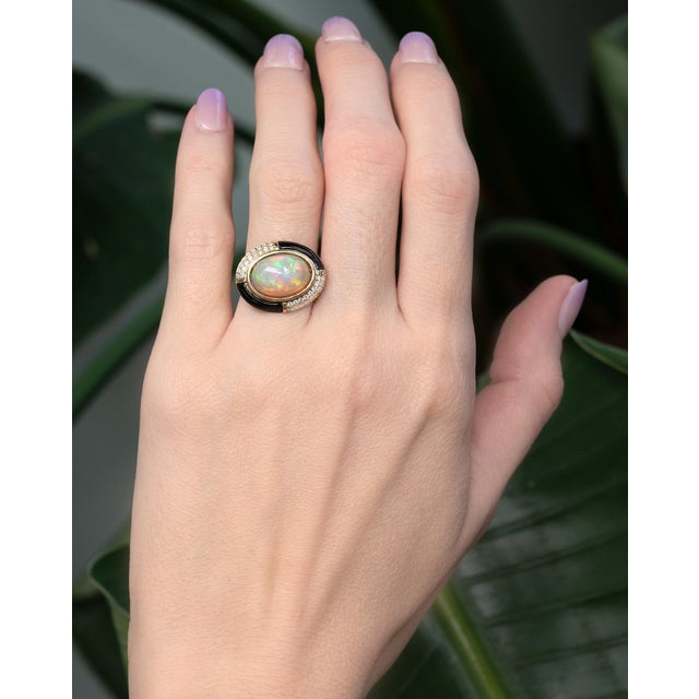 A captivating 5.3Ct oval opal (14×10mm) glows with enchanting flashes of color, framed by sparkling natural diamond...