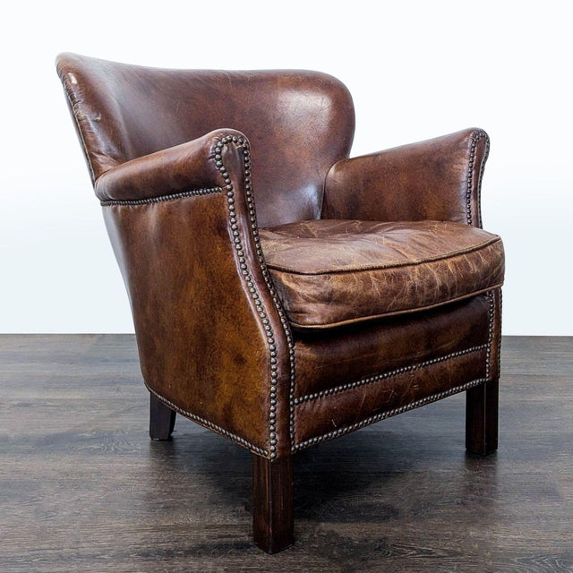 This Restoration Hardware lounge chair features rich brown leather upholstery with stylish nailhead trim. The seat is...