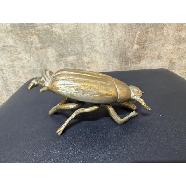 A beetle cast in solid brass, with a ribbed wing cover, a segmented thorax plate, a detailed head with eye and antennae,...