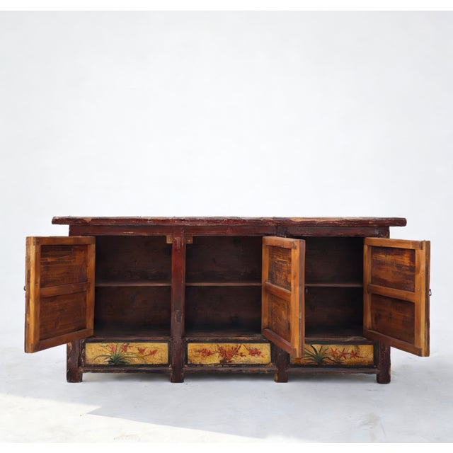 This late 19th century sideboard is handmade using sturdy pine and features vibrant, hand-painted floral panels on a warm...