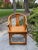 Traditional Chinese horseshoe chair in natural wood features elegant curves, a woven seat, an intricate fretwork carving...