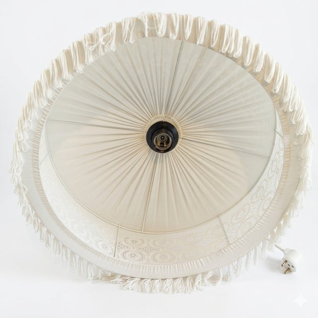 A poetic Swedish ceiling pendant from the 1970s, combining two classical Nordic hand-craft traditions in a single fixture....