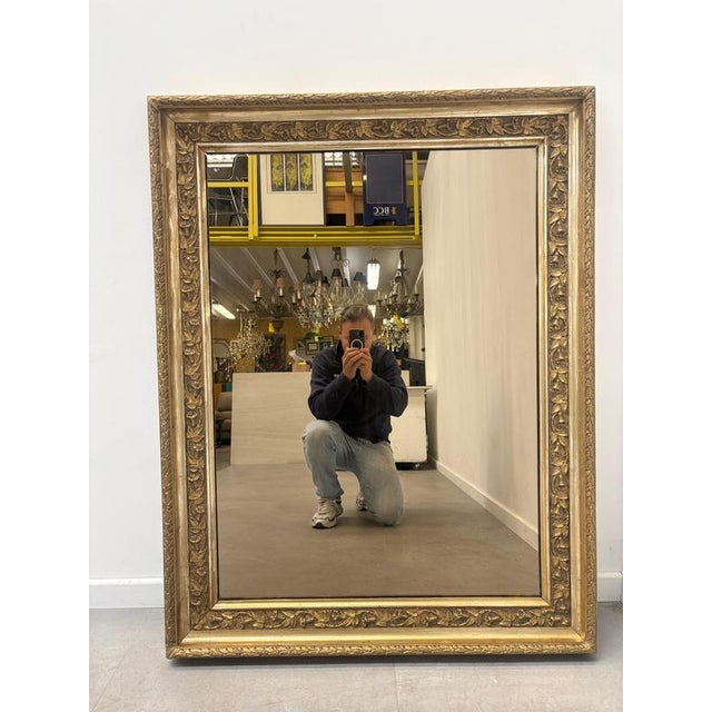 Elegant rectangular mirror featuring a richly decorated gold-tone frame with scrolling foliage and floral motifs. The...