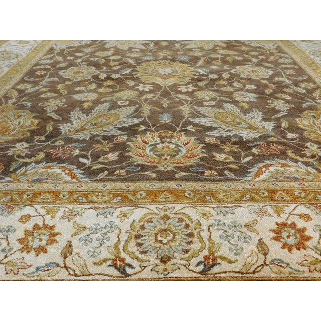An attractive rug with floral decoration on a light chocolate brown field within ivory vanilla border. Hand spun wool pile...