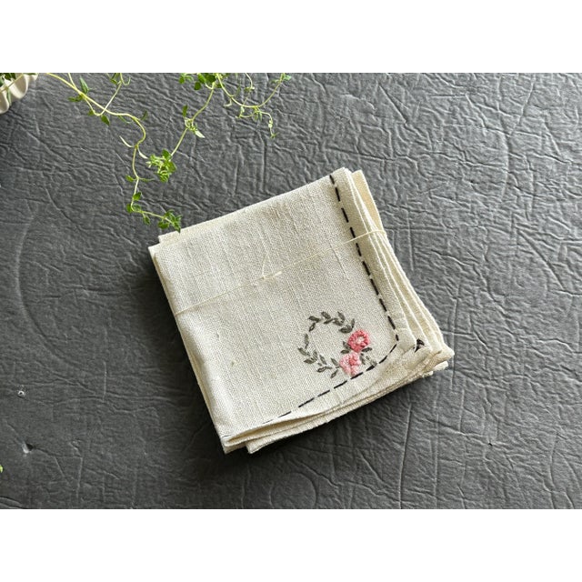 Skillfully handmade and embellished with hand-embroidered floral wreaths, this heirloom-quality linen cloth napkin set is...