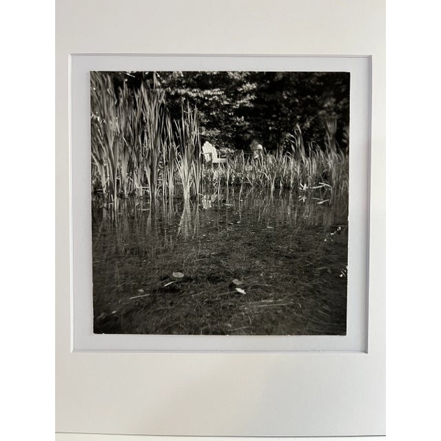 Contemporary digital print of original photograph by J. Peter Kieval of an Adirondack chair amongst reeds in water....