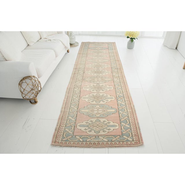 This is a vintage Turkish Oushak rug from the Mid 20th Century. The piece was hand-knotted.