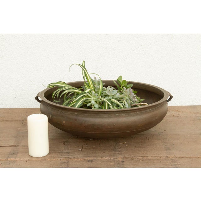 This 23-inch Urli is a significant found artifact, hand-cast by master metalsmiths in Kerala using the heritage lost-wax...