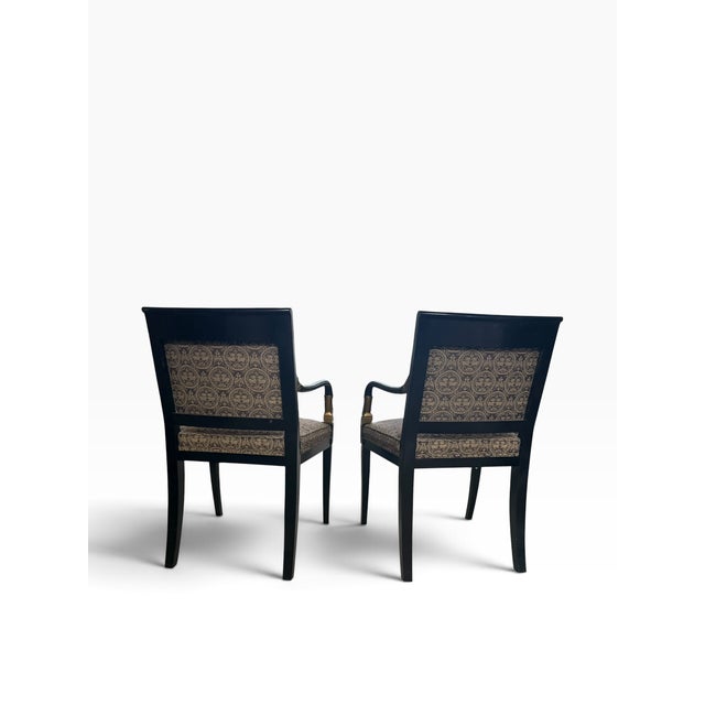 Beautiful pair of classic accent chairs featuring black wood frames, ornate gold detailing, and elegant black-and-gold...