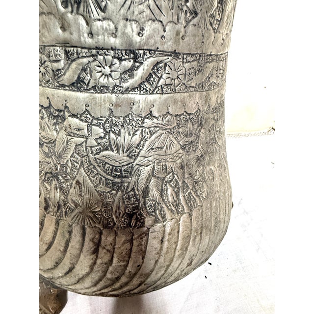 This is an antique Persian silver-washed copper can from the late 19th century. It has beautiful hammered engraving with...