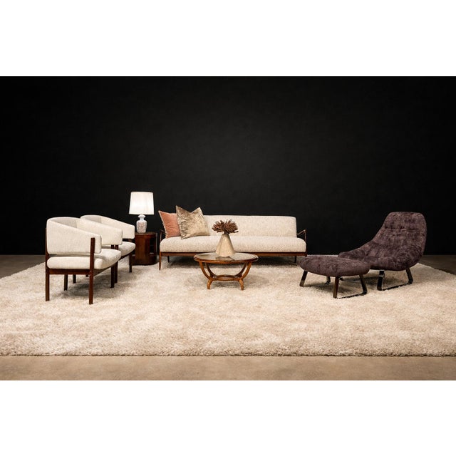 This pair of armchairs presents a measured dialogue between sculpted rosewood and tailored upholstery, characteristic of...