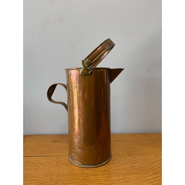 This 19th-century English copper jug—likely once used as a measuring pail—carries the quiet poetry of honest work and...