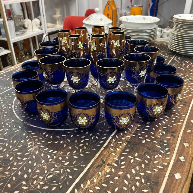 Gorgeous set of 31 cobalt blue handmade glasses from The Czech Republic. They have a lot of applied raised gold with hand...