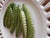 This exquisite Italian ceramic wall plate showcases a delightful design featuring peas nestled in their pods, all set...