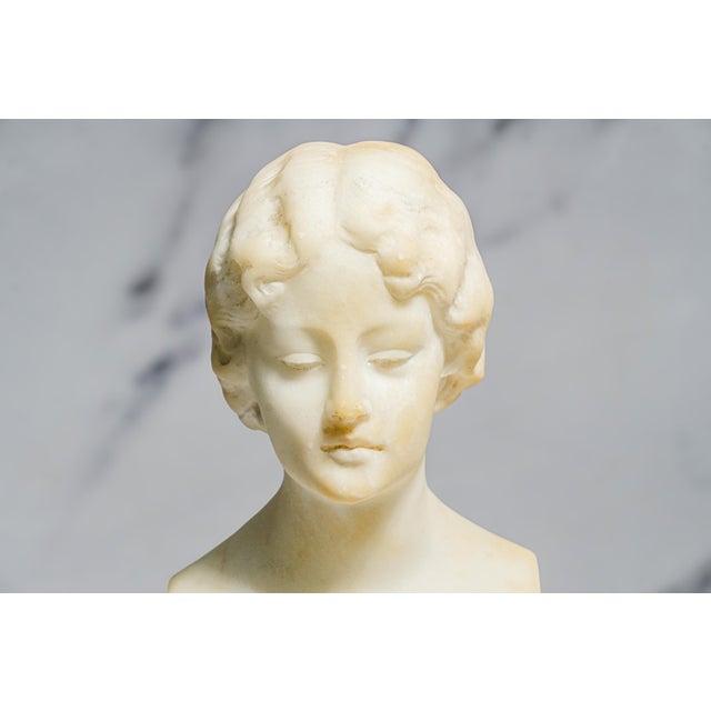 A refined example of early 20th-century neoclassical sculpture, this antique hand-carved marble bust dates to circa 1915...