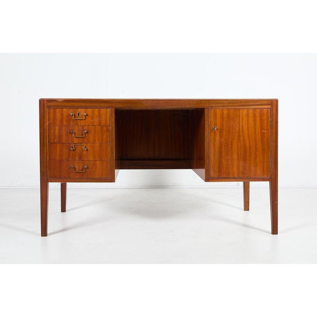 This minimalistic design mahogany veneer desk was produced in 1950’s, Denmark. It features various drawers, brass...