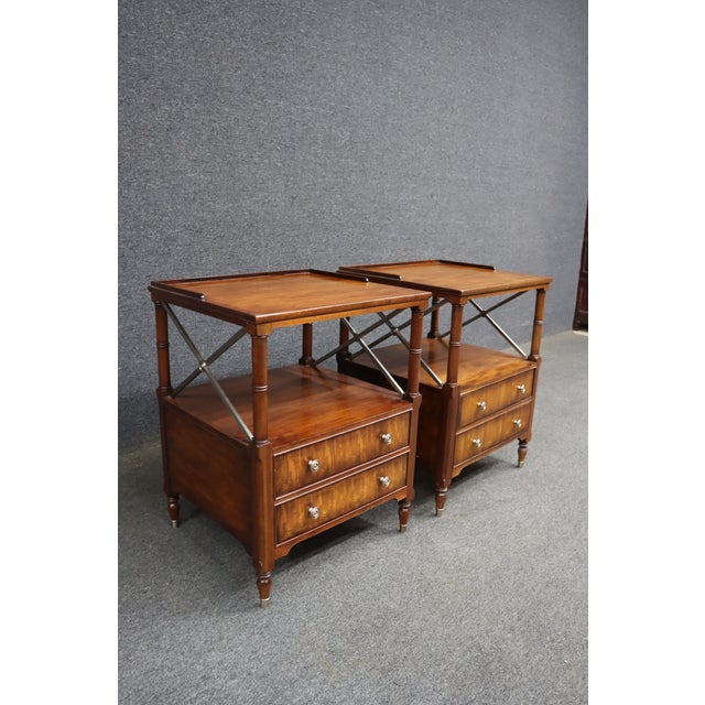 Pair of Ethan Allen bedside tables crafted in mahogany with raised gallery tops, open shelving, and two drawers each....